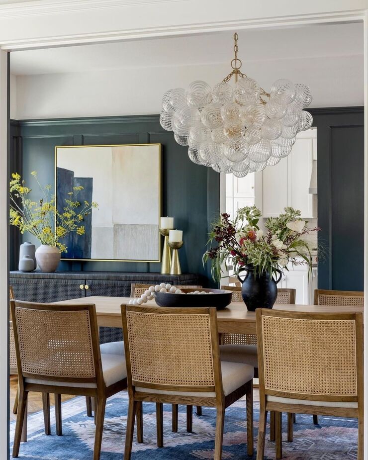 Designer Lauren Evans used the Talia Large Glass Chandelier in Gild as a dramatic complement to this dining room’s subtler elegance. Also shown are the Aimee Cane Side Chairs in Natural/Flax. Photo by Vivian Johnson.
